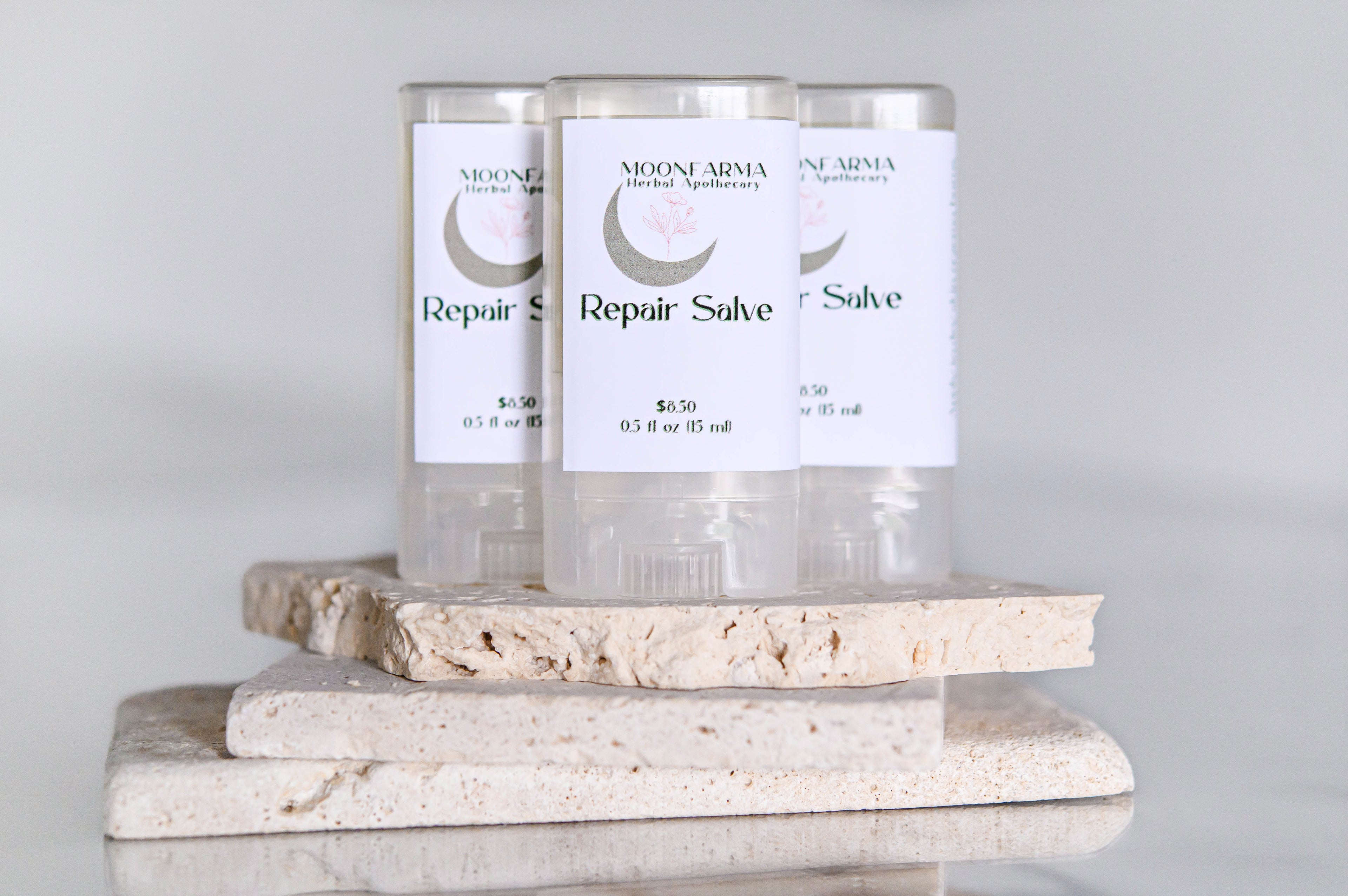 Three jars of Skin Repair Salve are displayed on a smooth surface, with the brand and product name visible on the labels.